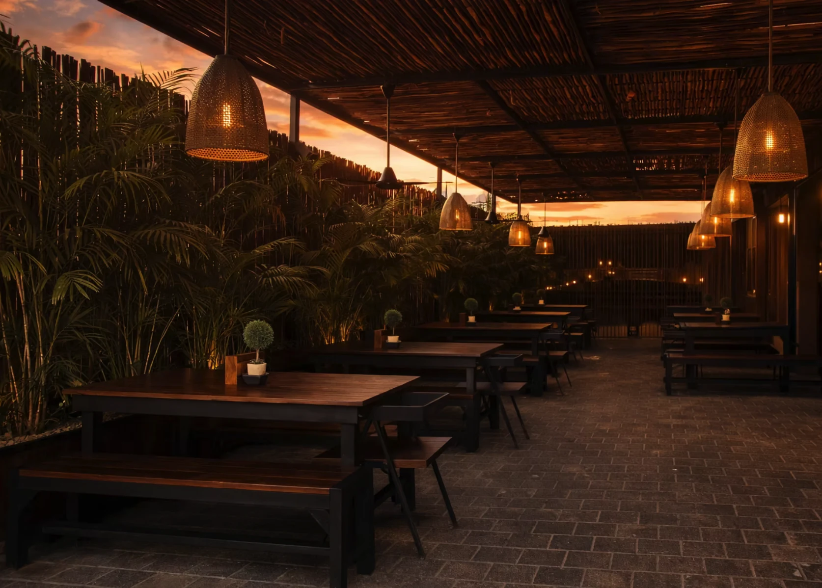 Terraza de restaurante al atardecer con mesas y bancas de acero y madera ALANKA